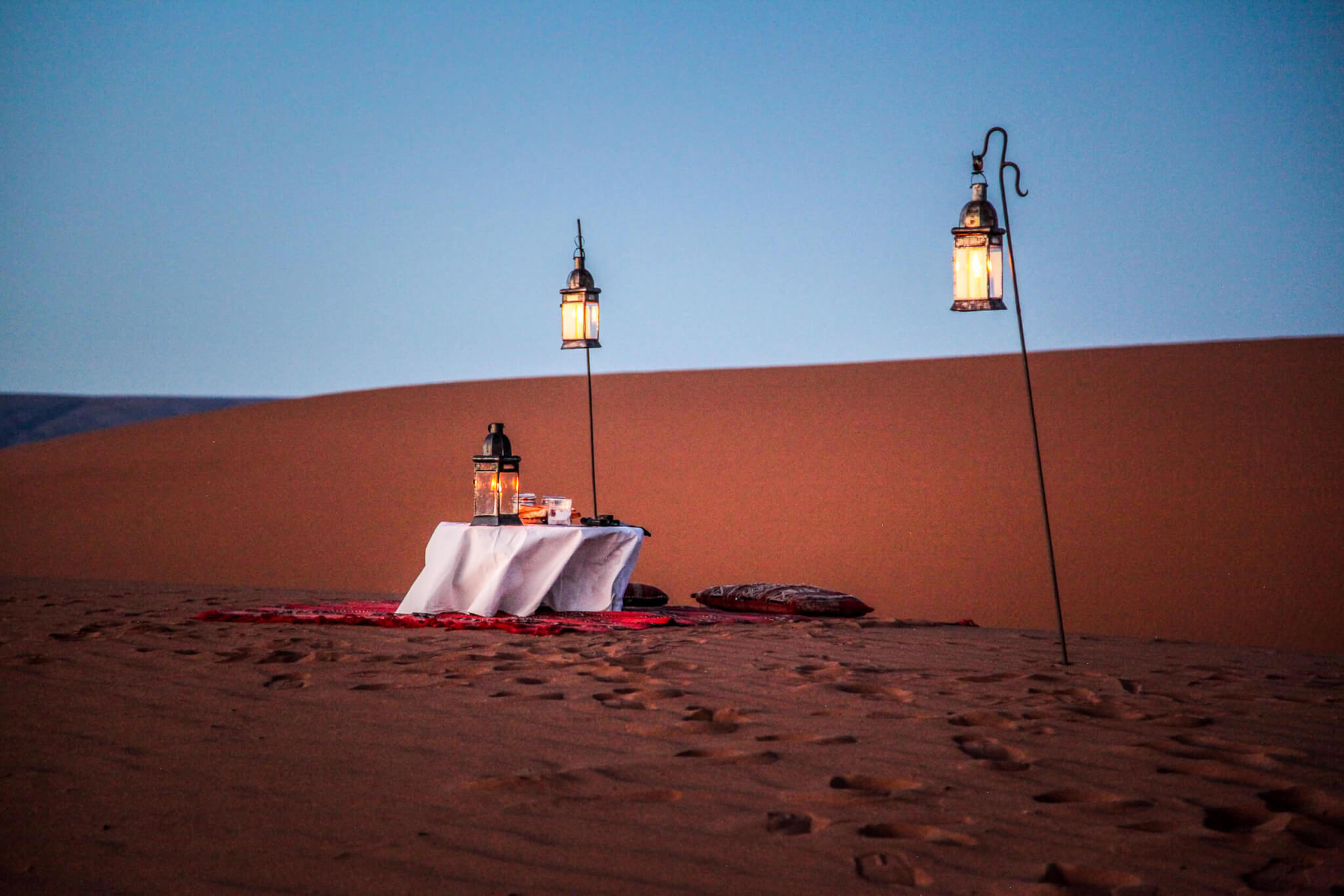 Sunset table with lanterns Dar Ahlam desert camp